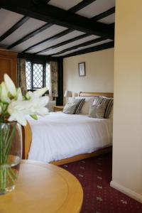 ein Schlafzimmer mit einem Bett und einem Tisch mit einer Blumenvase in der Unterkunft The Brickwall Hotel in Sedlescombe