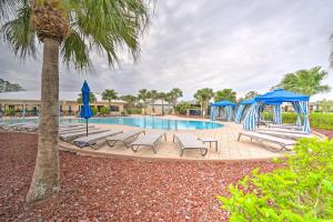 una piscina con tumbonas y sombrillas azules en Pet-Friendly Sebring Home with Golf and Pool Access, en Sebring