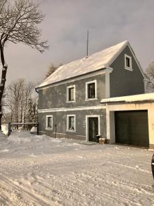 una casa gris con un garaje en la nieve en Apartmány Razová - Slezská Harta, en Razová