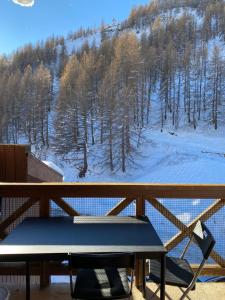 stół piknikowy na balkonie z pokrytą śniegiem górą w obiekcie Charmant studio avec coin nuit en mezzanine La Foux d'Allos w mieście Allos