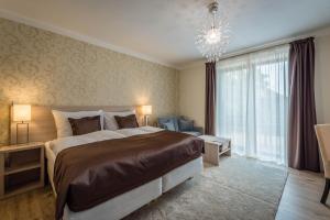a bedroom with a large bed and a chandelier at Vila Monika in Tvrdošovce