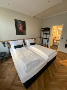 a large white bed in a bedroom with wooden floors at Boutique Hotel Kolbeck in Vienna