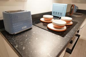 a kitchen counter with four bowls and a toaster at Peaceful Luxury Apartment in Croydon