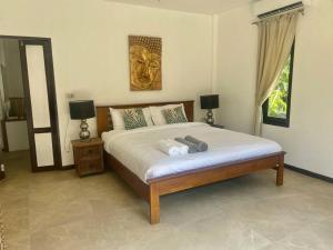 a bedroom with a bed with two lamps and a lion on the wall at Bamboo Villa in Ko Tao