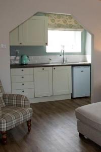 a kitchen with white cabinets and a sink and a window at Rooftops in Louth