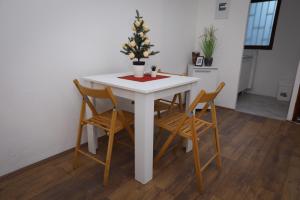 een witte tafel met twee stoelen en een kerstboom erop bij Central Studio Apartman in Šabac
