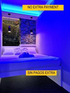 Cama en habitación con luz azul en Modular Rooms, en Madrid