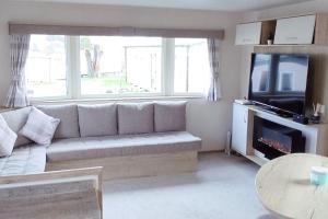 a living room with a couch and a tv and a table at Paddock 39 Caravan - Weymouth Bay in Preston
