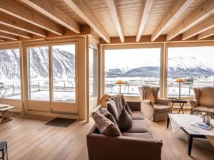 uma sala de estar com um sofá, cadeiras e janelas em Apartment Chesa Crusch 7 by Interhome em Samedan