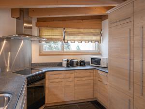 eine Küche mit Holzschränken und einer Mikrowelle in der Unterkunft Apartment Chesa Crusch 7 by Interhome in Samedan