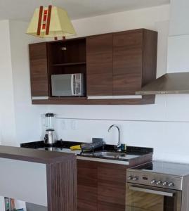 cocina con armarios de madera, fregadero y microondas en Apartamento con vistas, en Montevideo
