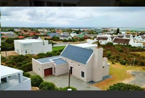 a large white house with a solar roof at Four Steenbras in Struisbaai