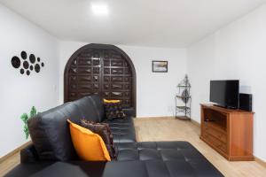 a living room with a black leather couch and a television at La Esperanza downtown 3 bd apt in El Rosario