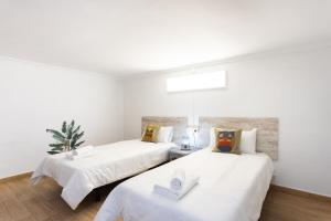 2 Betten in einem Zimmer mit weißen Wänden in der Unterkunft La Esperanza downtown 3 bd apt in El Rosario