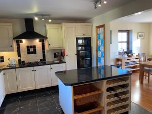 a kitchen with white cabinets and a black counter top at Stunning hideaway on the Wild Atlantic Way in Knocknaud