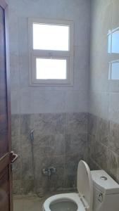 y baño con aseo, ventana y ducha. en Reef 18 by Al Azmy en Riad
