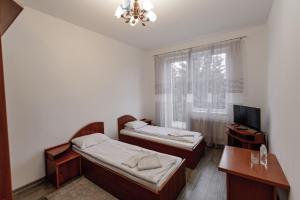 a room with two beds and a desk and a television at Готель Яблуниця in Yablunytsya