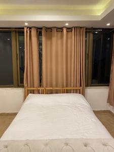 a bed in a room with curtains and windows at The view II in Amman