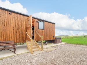ein winziges Holzhaus mit einer Treppe neben einer Bank in der Unterkunft Hillcrest Shepherds Hut in Preston