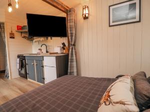 a room with a bed and a kitchen with a tv at Hillcrest Shepherds Hut in Preston