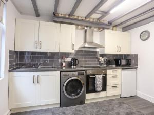 a kitchen with white cabinets and a washing machine at Llys Mair in Bala