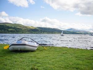 ein Boot, das auf dem Gras neben einem Wasserkörper sitzt in der Unterkunft Llys Mair in Bala