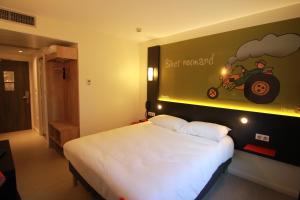 a bedroom with a bed with a sign on the wall at ibis Styles Flers in Flers
