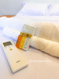 a bottle of essential oil next to a book on a bed at Apartamento frente mar c/ar P/ 6 hóspedes in São Vicente