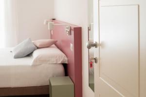 a small bedroom with a bed with a pink headboard at La Rosa rooms & holiday home in Porto SantʼElpidio +29 photos