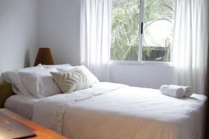 圣塔特蕾莎海滩Outsite Santa Teresa Playa的卧室里有一张铺着白色床单的床和一扇窗户