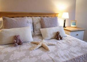 two teddy bears sitting on a bed with two starfish at Host & Stay - View Point Apartment in Hinderwell