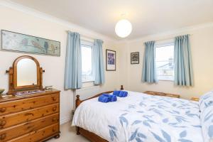 a bedroom with a bed and a dresser and windows at Hope House in East Cowes