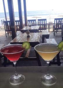 two cocktails sitting on a table with a view of the ocean at Fernandes Bar and Restaurant in Canacona