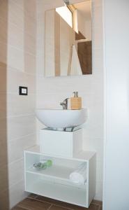 Baño blanco con lavabo y espejo en Maison L'amuri, en Palermo