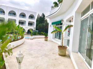 une cour d'un bâtiment blanc avec une plante en pot dans l'établissement Residence Royal - Deluxe, à Hammamet Sud