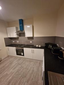 a kitchen with white cabinets and a black counter top at LaLuNa One Bedroom Apartment Newcastle in Elswick