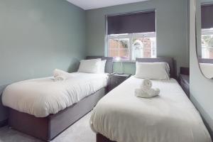 two beds in a room with two windows at Air Host and Stay - Wright Terrace, 4 bedroom, 2 bathroom sleeps 8 in Liverpool