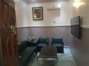 una sala de espera con 2 sofás verdes y TV en Haven Suites, Ikenegbu en Owerri