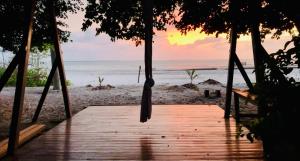 - une balançoire sur la plage avec un coucher de soleil en arrière-plan dans l'établissement FlowMove Retreat Algodoal, à Algodoal