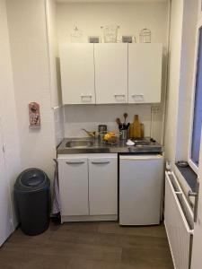 a small kitchen with white cabinets and a sink at jolie studio in Arras