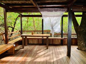 une terrasse couverte en bois avec une table et un filet dans l'établissement FlowMove Retreat Algodoal, à Algodoal