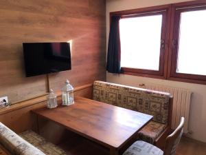 een eetkamer met een houten tafel en een televisie bij Paradise Dolomiti flat in Falcade