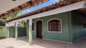 a green house with a green wall and a door at Recanto dos Jardim's Arraial do Cabo in Arraial do Cabo