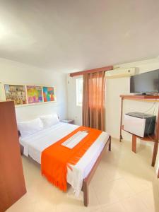 a bedroom with a bed with an orange blanket on it at Hotel La Guajira in Ríohacha