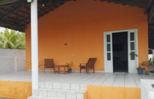 a house with two chairs and a patio at Casa frente para o mar in Nova Viçosa