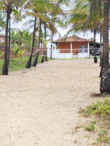 a beach with palm trees in front of a house at Casa frente para o mar in Nova Viçosa