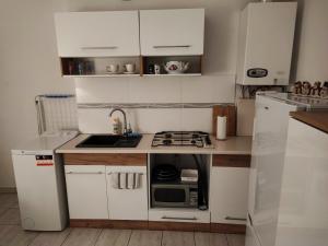 a kitchen with white cabinets and a sink and a microwave at Apartament - Mieszkanie Samodzielne in Inowrocław