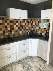 a kitchen with white cabinets and a tile wall at Charming Studio With Terrace And 180 Sea View in Six-Fours-les-Plages