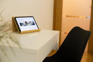 a tablet sitting on a white table with a black chair at Apartman Čakovec in Čakovec