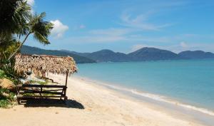 a bench on a beach next to the ocean at Penang 5bedroom Bungalow with pool in Batu Ferringhi